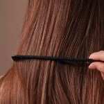 Geglättete Haarlängen werden mit einem Kamm durchgekämmt – ruhige Haarstruktur nach der Anwendung einer Anti Frizz Creme