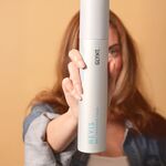 Frau hält GLYNT NEVIS Trockenshampoo Schaum Dose frontal in die Kamera, Produkt im Fokus vor unscharfem Hintergrund, Dry Shampoo Foam für frisches Haar und mehr Volumen ohne Waschen