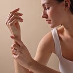 Frau pflegt trockene Hände und Handgelenk mit einer Handcreme für trockene Haut – sanfte Pflegebewegung für geschmeidige Haut