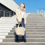 Frau auf Treppe mit beiger GLYNT Stofftasche „looks good on you“ in urbaner Umgebung.