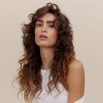 Frau mit langen, definierten, dunklen Locken und natürlichem Volumen – Beispiel für Lockenstyling bei Frauen