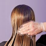 Anti-Gelbstich Maske mit violetten Pigmenten wird in blondes, nasses Haar einmassiert.