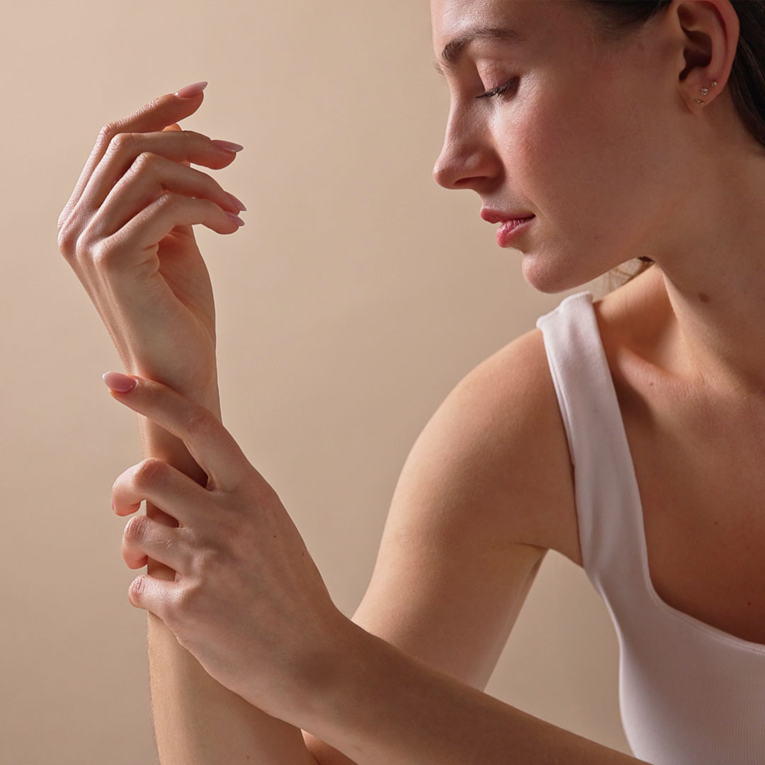 Frau pflegt trockene Hände und Handgelenk mit einer Handcreme für trockene Haut – sanfte Pflegebewegung für geschmeidige Haut