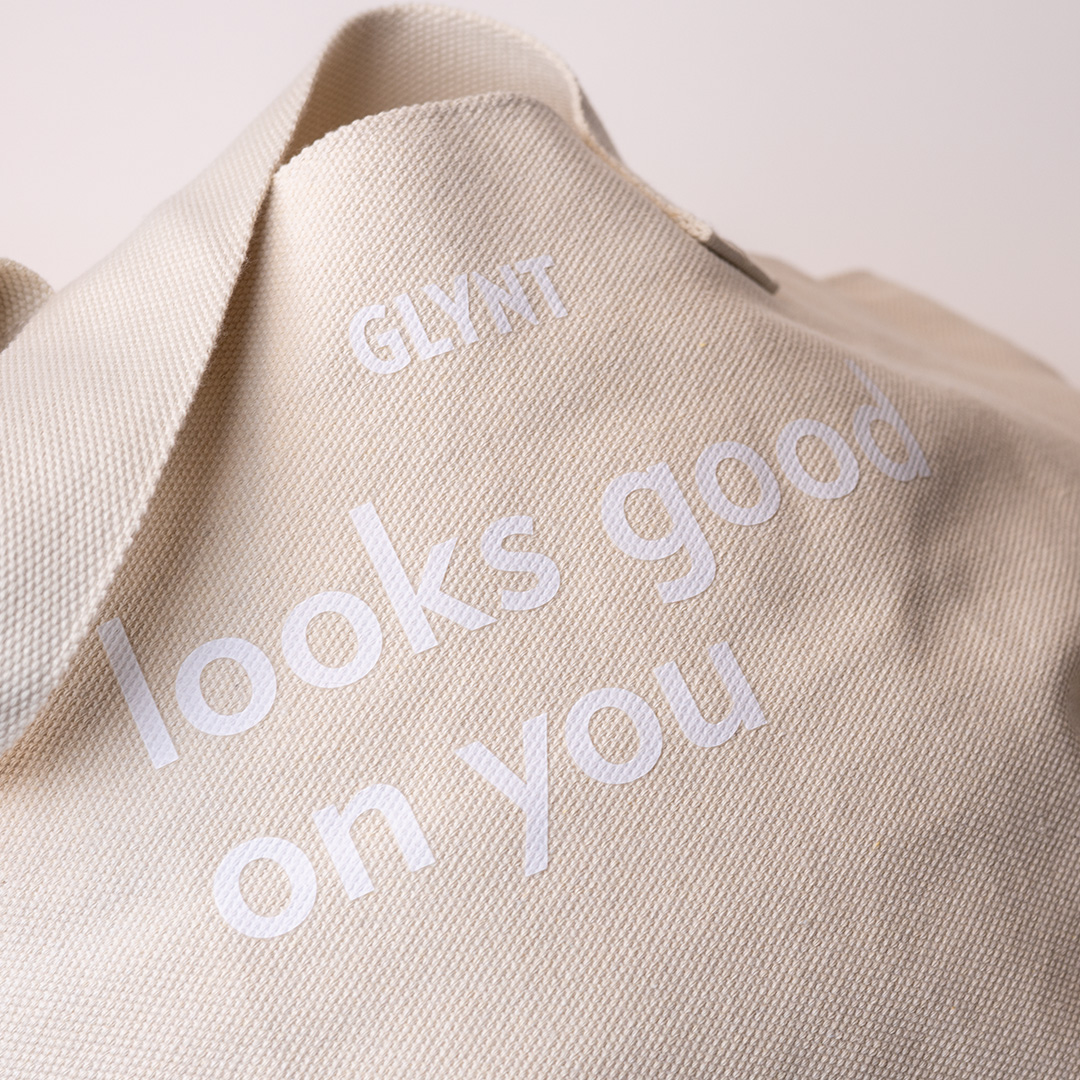 Beige GLYNT Stofftasche mit Aufdruck „looks good on you“, Nahaufnahme des Materials.